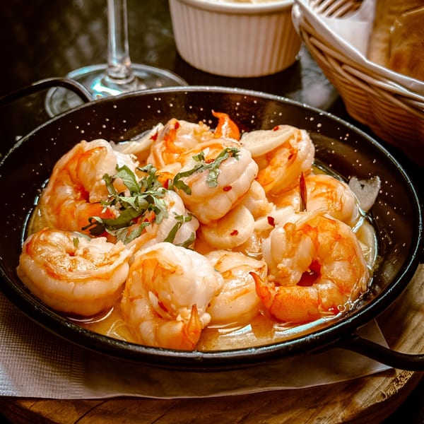 Tio Pepe's Spanish garlic shrimp (gambas al ajillo) in a black skillet, garnished with herbs.